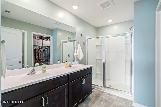 bathroom featuring a shower with door and vanity