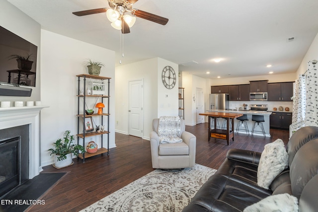 living room featuring ceiling fan and dark hardwood / wood-style flooring