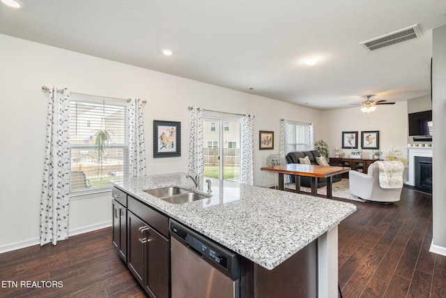 kitchen with dark brown cabinetry, sink, stainless steel dishwasher, dark hardwood / wood-style floors, and an island with sink