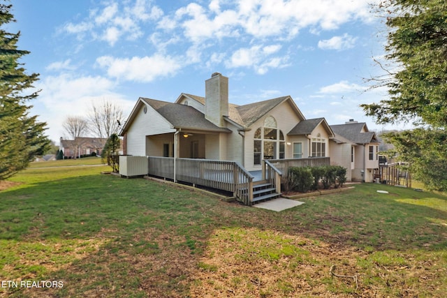 back of property featuring a deck, a lawn, and a chimney