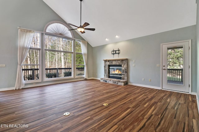 unfurnished living room with a wealth of natural light, a stone fireplace, high vaulted ceiling, and wood finished floors