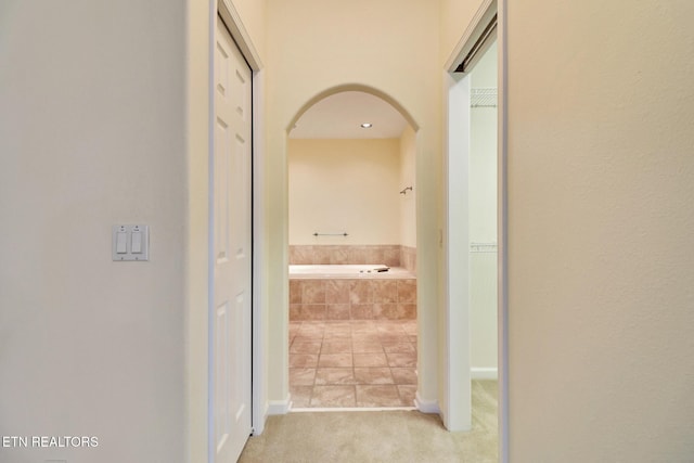 corridor with arched walkways and carpet flooring