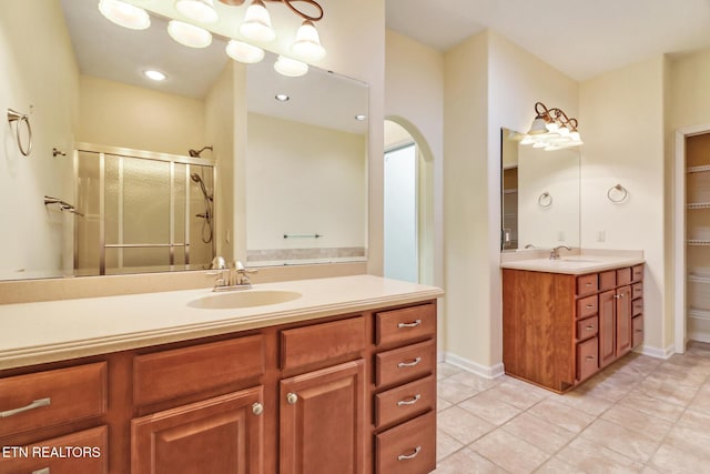 bathroom with tile patterned floors, a shower stall, vanity, and baseboards