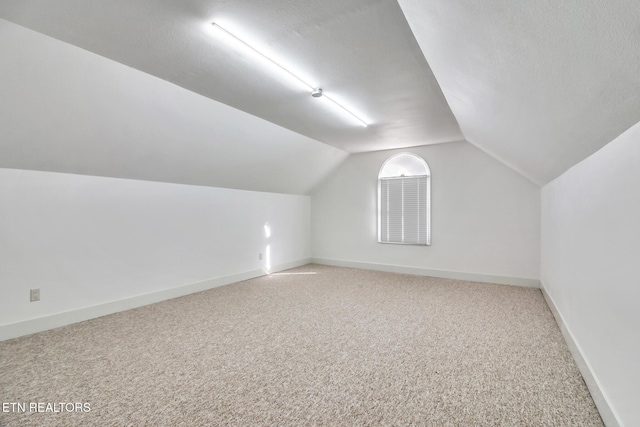 bonus room with a textured ceiling, baseboards, lofted ceiling, and carpet