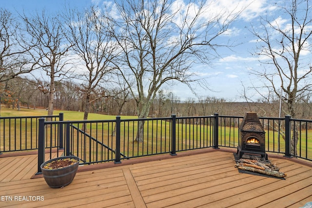 wooden terrace with exterior fireplace and a lawn