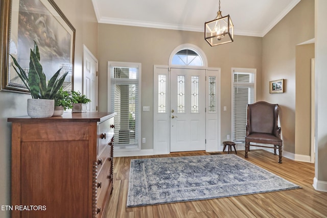 foyer entrance with hardwood / wood-style flooring, crown molding, and an inviting chandelier