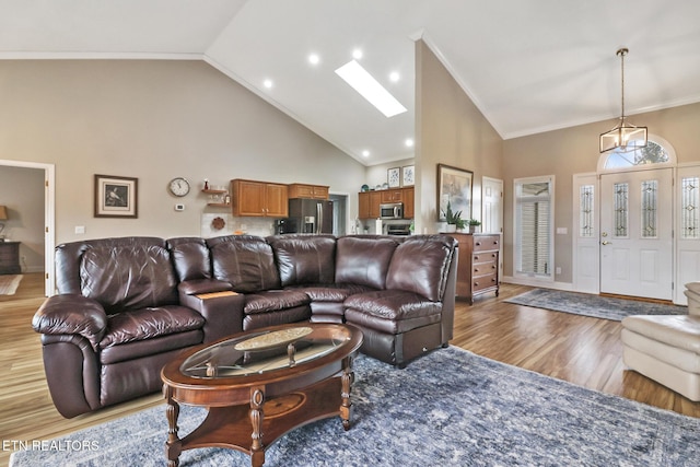 living room featuring ornamental molding, high vaulted ceiling, light hardwood / wood-style floors, and a skylight