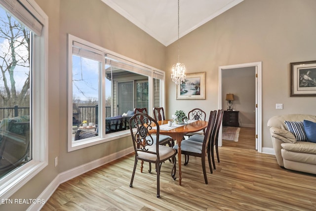 dining area with high vaulted ceiling, hardwood / wood-style floors, and a chandelier