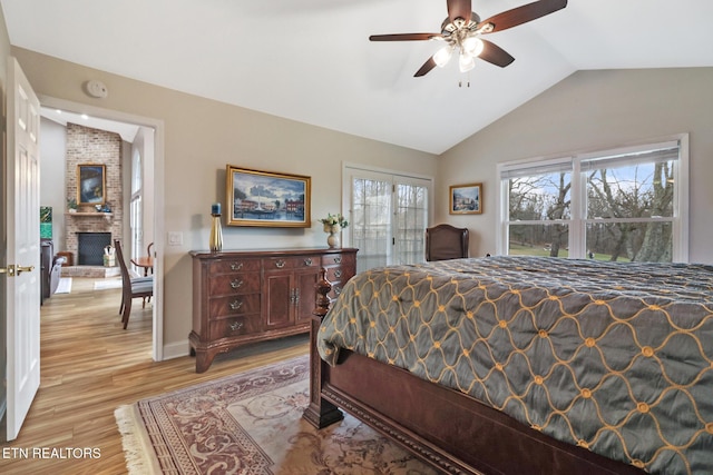 bedroom with light hardwood / wood-style flooring, a fireplace, and vaulted ceiling