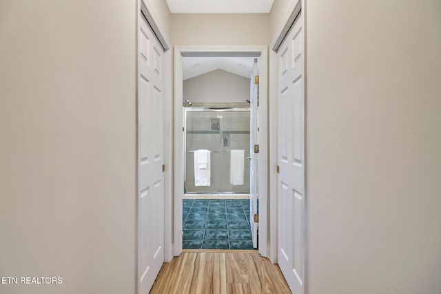 hallway with vaulted ceiling and light hardwood / wood-style floors