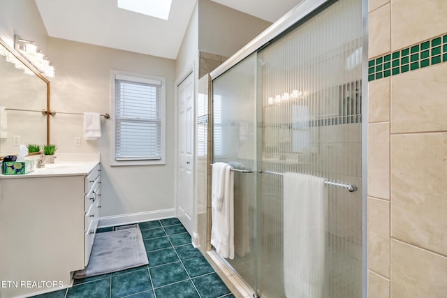 bathroom with vanity, a shower with door, a skylight, and tile patterned flooring