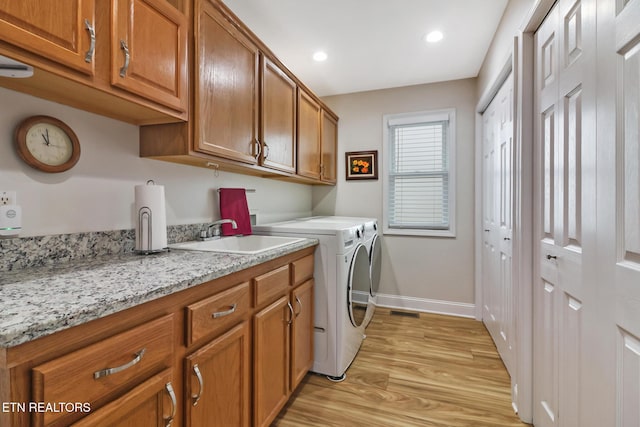 washroom with cabinets, separate washer and dryer, sink, and light hardwood / wood-style floors