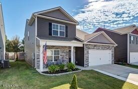 view of front of house featuring central AC unit, a garage, a front lawn, and a porch