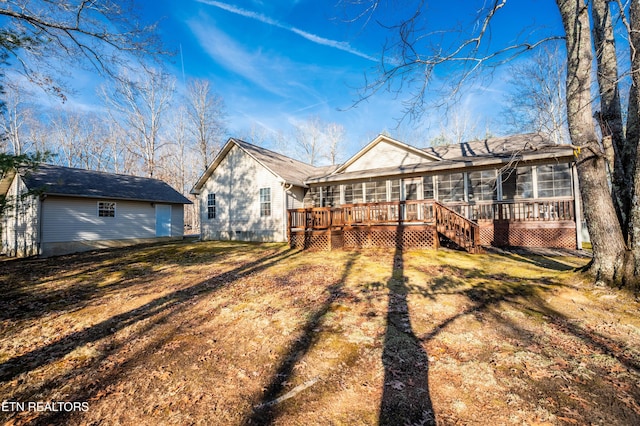 rear view of property with a wooden deck, a sunroom, and a yard