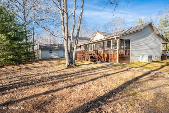 rear view of property featuring central AC unit, a yard, a sunroom, and a wooden deck