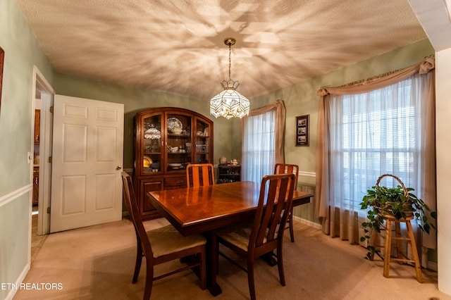 dining area with light colored carpet and a textured ceiling