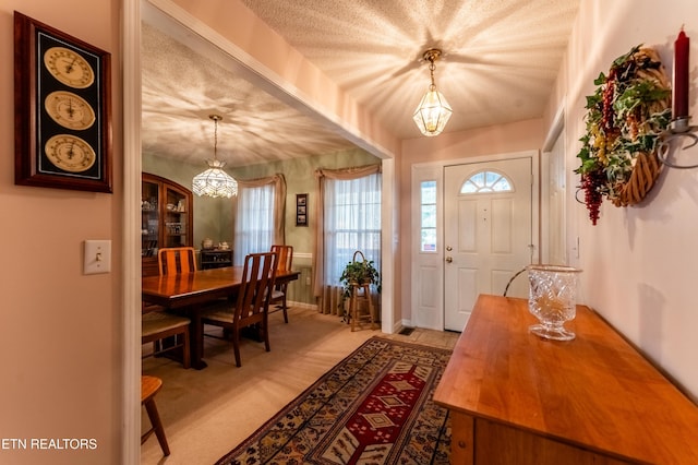 carpeted entryway with a chandelier and a textured ceiling