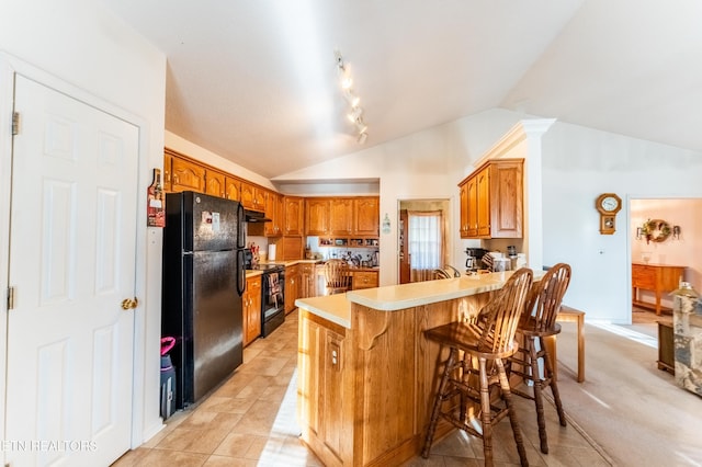 kitchen with extractor fan, black appliances, lofted ceiling, a breakfast bar area, and kitchen peninsula