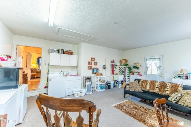 living room featuring light carpet, washer and clothes dryer, and a textured ceiling