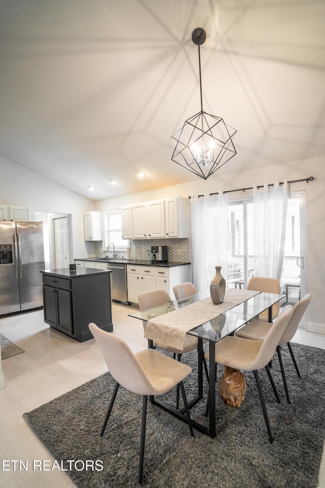 dining area with lofted ceiling, a chandelier, and sink