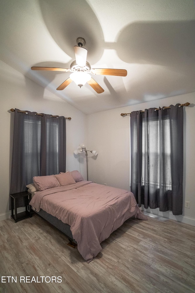 bedroom featuring hardwood / wood-style flooring, ceiling fan, and lofted ceiling