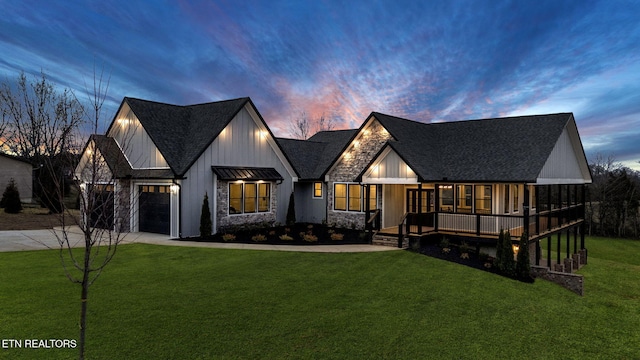 modern inspired farmhouse with metal roof, an attached garage, a yard, driveway, and a standing seam roof