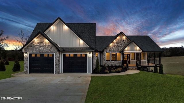 modern farmhouse with a shingled roof, concrete driveway, an attached garage, a yard, and board and batten siding