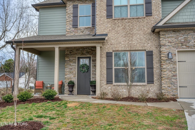 entrance to property with a yard, a garage, and a porch