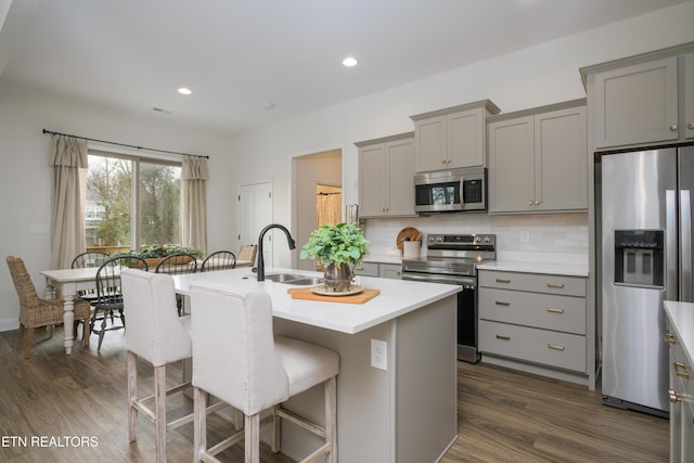 kitchen featuring stainless steel appliances, an island with sink, sink, and gray cabinetry