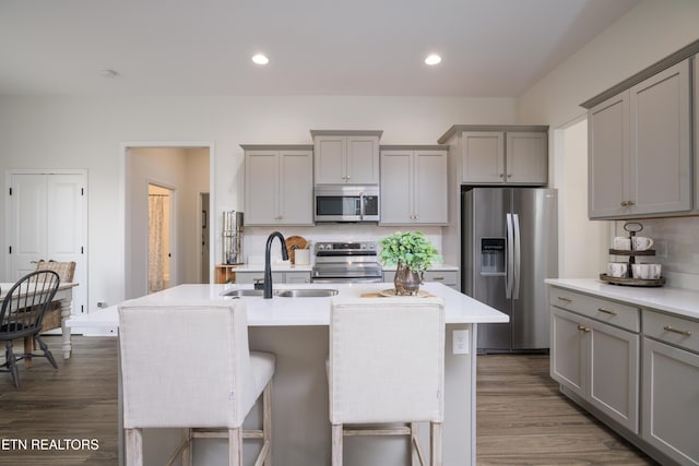 kitchen featuring gray cabinets, appliances with stainless steel finishes, sink, and a center island with sink