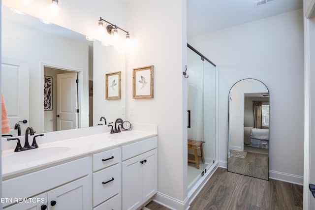 bathroom featuring wood-type flooring, a shower with shower door, and vanity