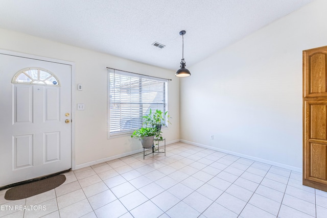 tiled entrance foyer with vaulted ceiling and a textured ceiling