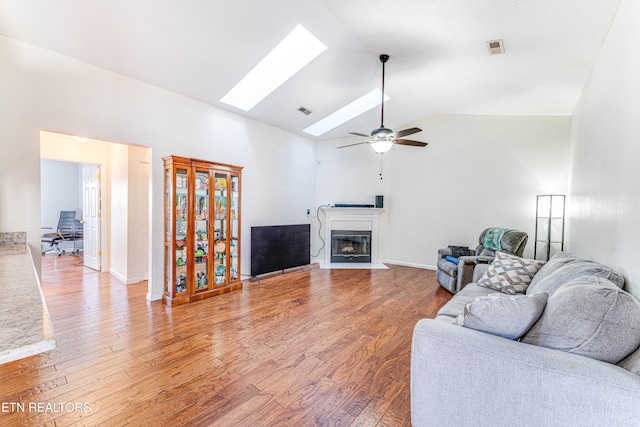 living room featuring wood-type flooring, high vaulted ceiling, ceiling fan, and a skylight