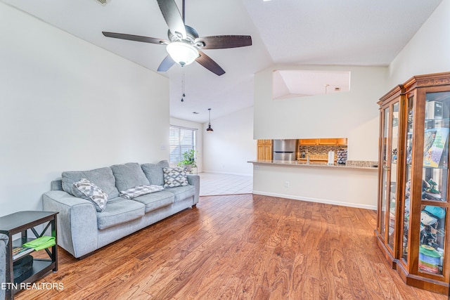 living room featuring ceiling fan, lofted ceiling, and light wood-type flooring