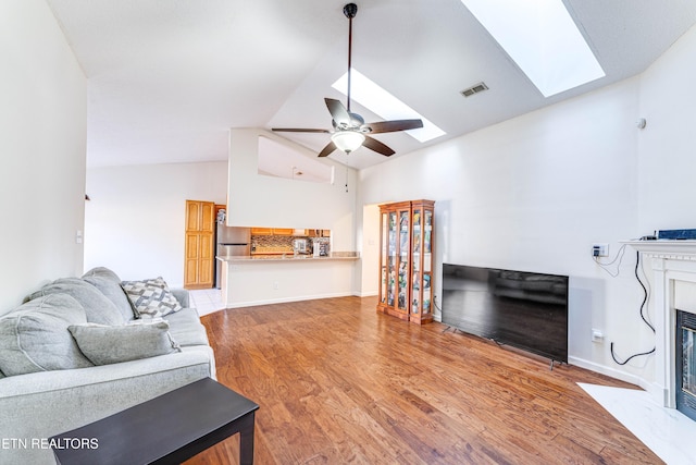 living room featuring hardwood / wood-style floors, lofted ceiling with skylight, and ceiling fan