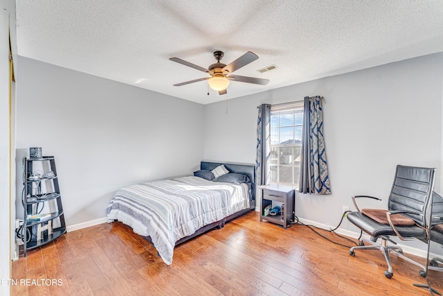 bedroom featuring hardwood / wood-style flooring, ceiling fan, and a textured ceiling