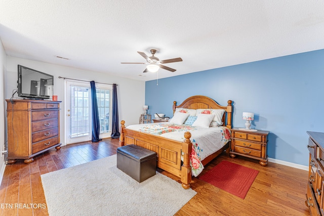 bedroom featuring access to exterior, ceiling fan, dark hardwood / wood-style floors, and a textured ceiling