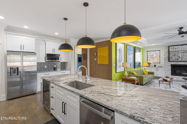 kitchen featuring decorative light fixtures, sink, stainless steel appliances, and white cabinetry