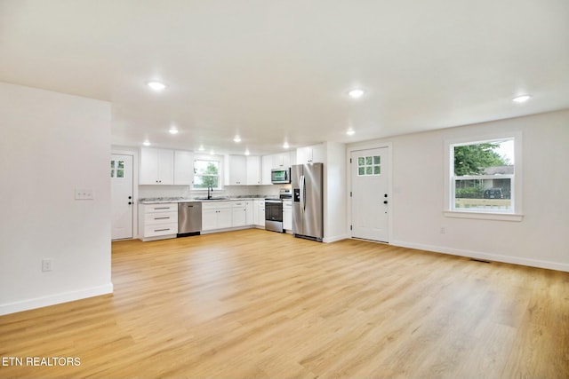 kitchen with appliances with stainless steel finishes, light hardwood / wood-style floors, sink, and white cabinets