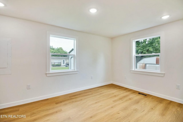 empty room with light hardwood / wood-style floors and electric panel