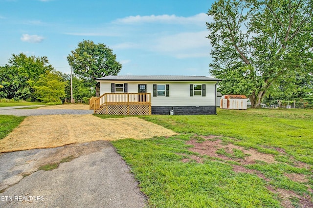 manufactured / mobile home with a wooden deck, a front lawn, and a storage unit