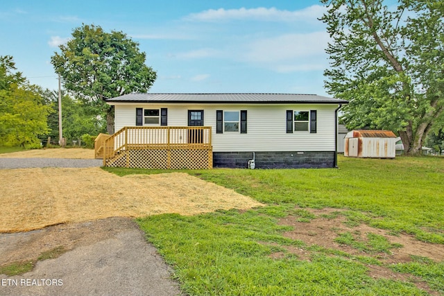 manufactured / mobile home with a wooden deck, a front lawn, and a storage unit