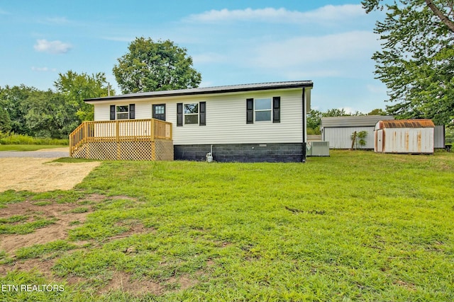 manufactured / mobile home with central AC unit, a front yard, a deck, and a storage shed