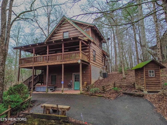 view of front of home featuring cooling unit, a storage shed, a wooden deck, and a patio