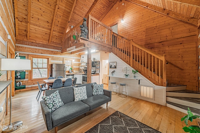 unfurnished living room with wood walls, wood ceiling, high vaulted ceiling, light hardwood / wood-style flooring, and beam ceiling