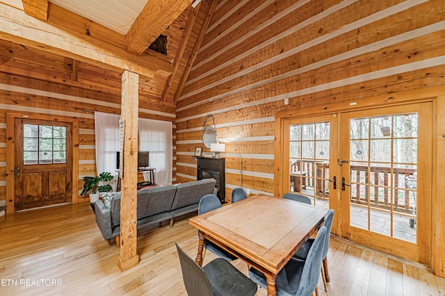 dining space featuring french doors, wood walls, wood ceiling, light hardwood / wood-style flooring, and beam ceiling