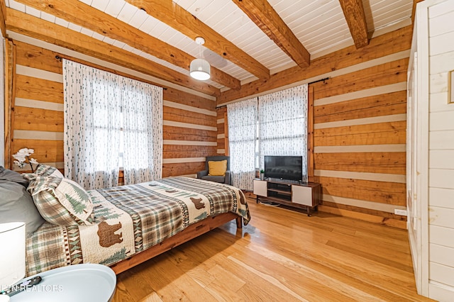 bedroom featuring beamed ceiling, wood ceiling, light hardwood / wood-style floors, and wood walls