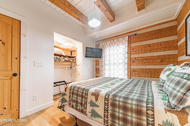 bedroom featuring beamed ceiling, hardwood / wood-style floors, wooden ceiling, and wood walls