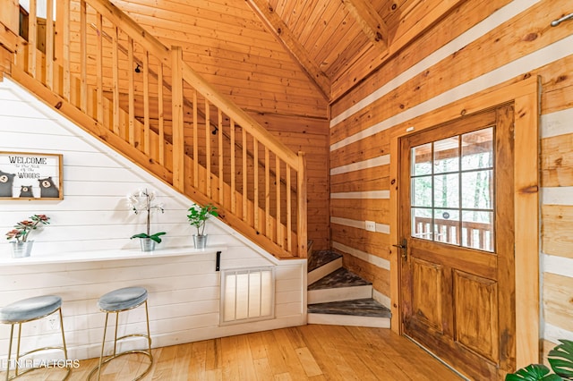 entryway featuring light hardwood / wood-style flooring, wooden walls, wooden ceiling, and lofted ceiling