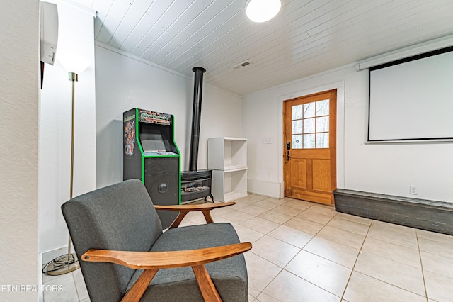 living area with light tile patterned flooring, a wood stove, and wood ceiling